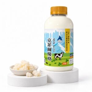 東歐嚴選｜kefir.link 原味牛奶克菲爾優格 500g 放在白色展示台上，旁邊一小碟克菲爾菌粒
