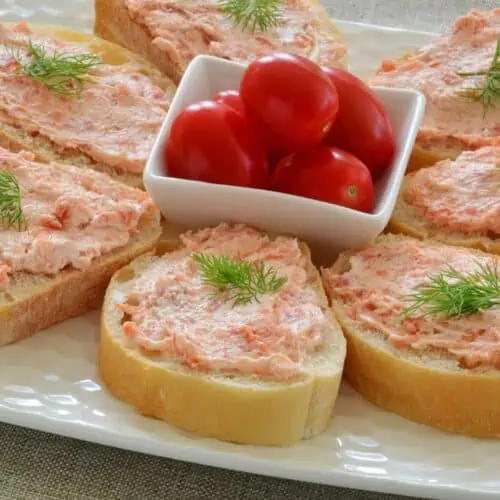 Slices of baguette topped with salmon kefir cheese spread and dill, with cherry tomatoes