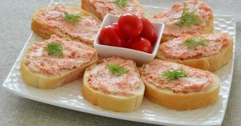 Slices of baguette topped with salmon kefir cheese spread and dill, with cherry tomatoes