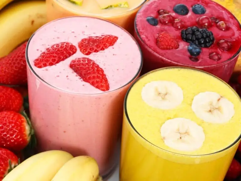 Glasses of strawberry, berry and banana smoothies topped with fresh fruit