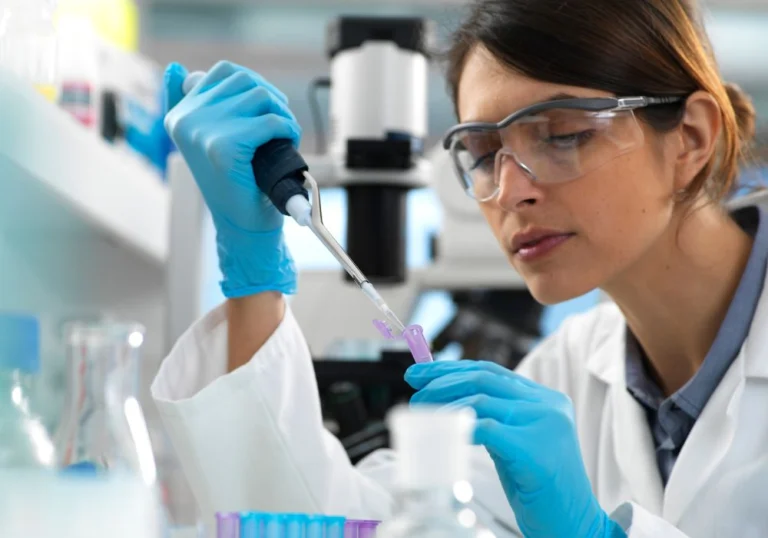 Lab scientist in gloves and safety glasses using a pipette, illustrating laboratory testing