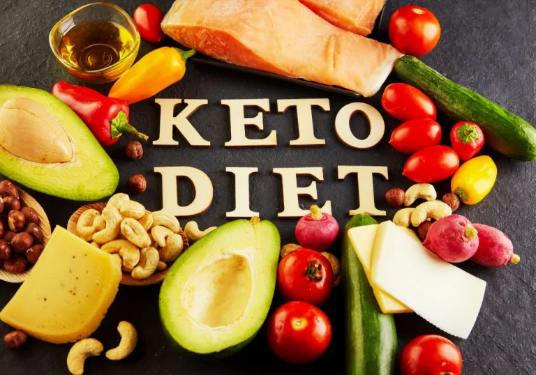 Wooden letters spelling KETO DIET surrounded by salmon, avocado, cheese, nuts and vegetables