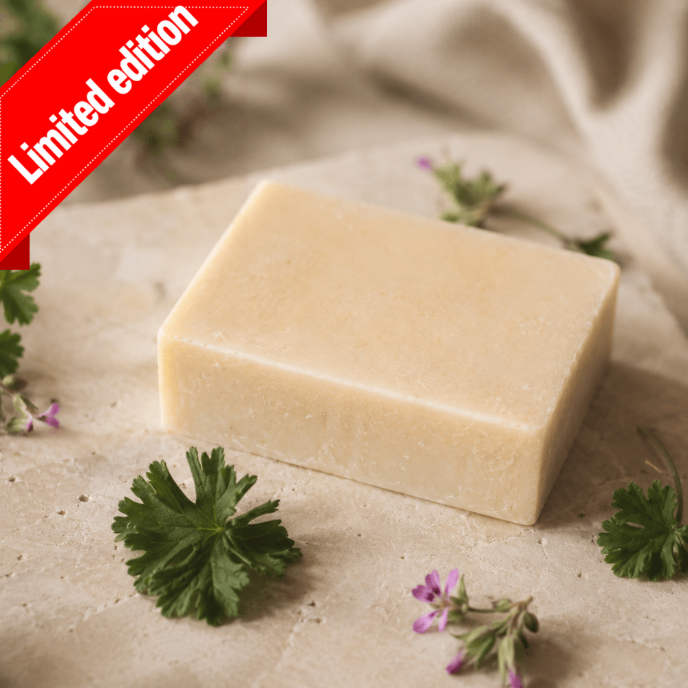 Limited-edition geranium kefir soap: a cream bar on stone with geranium leaves and small pink flowers